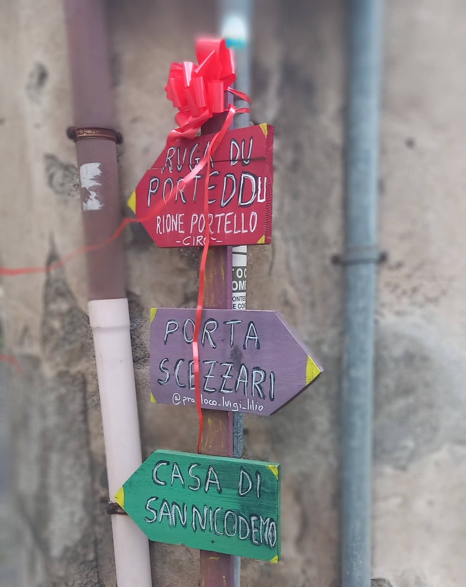 Hand-painted directional signs in Cirò's Portello district, including a sign for the House of San Nicodemo.